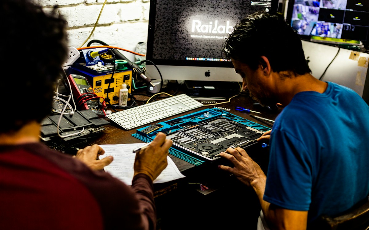Técnicos diagnosticando una computadora en un taller, sobre una mesa azul